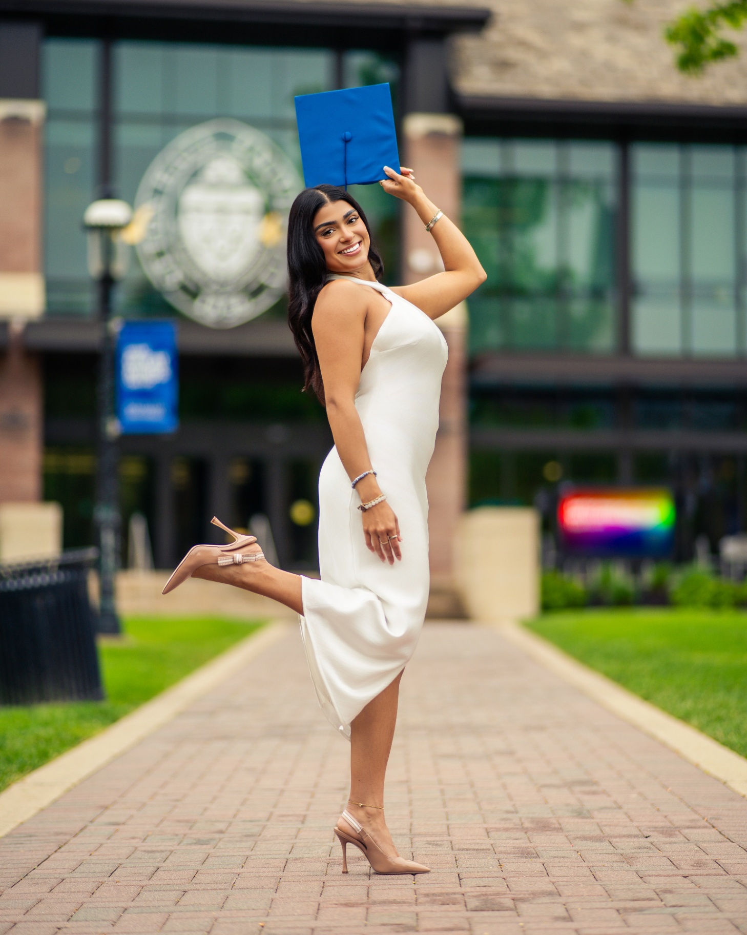 Seton Hall grad tossing cap in white dress on campus
