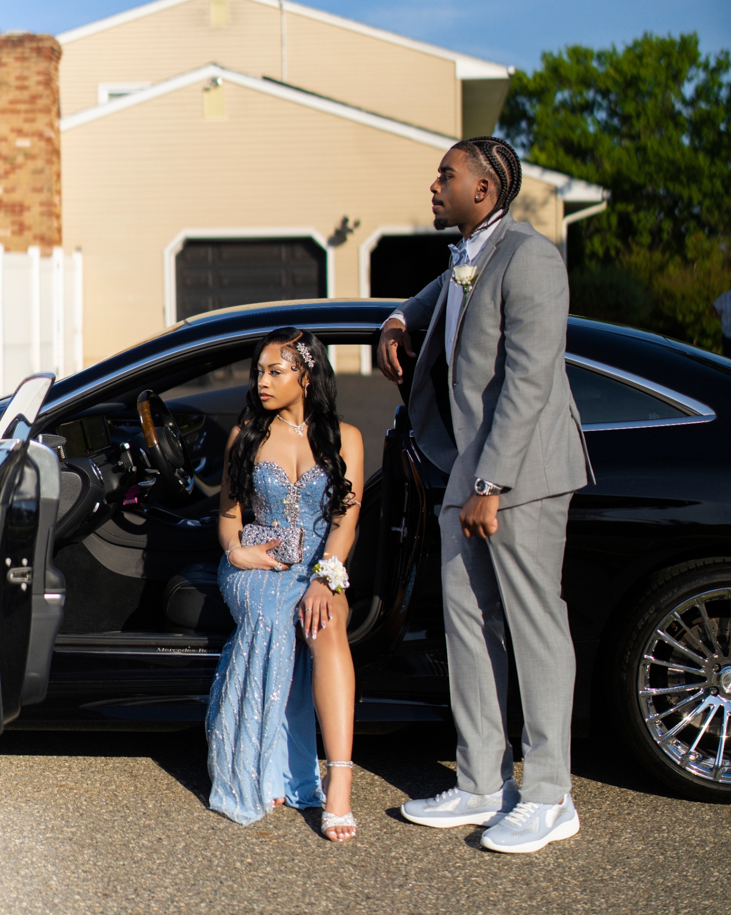 Prom couple posing with car
