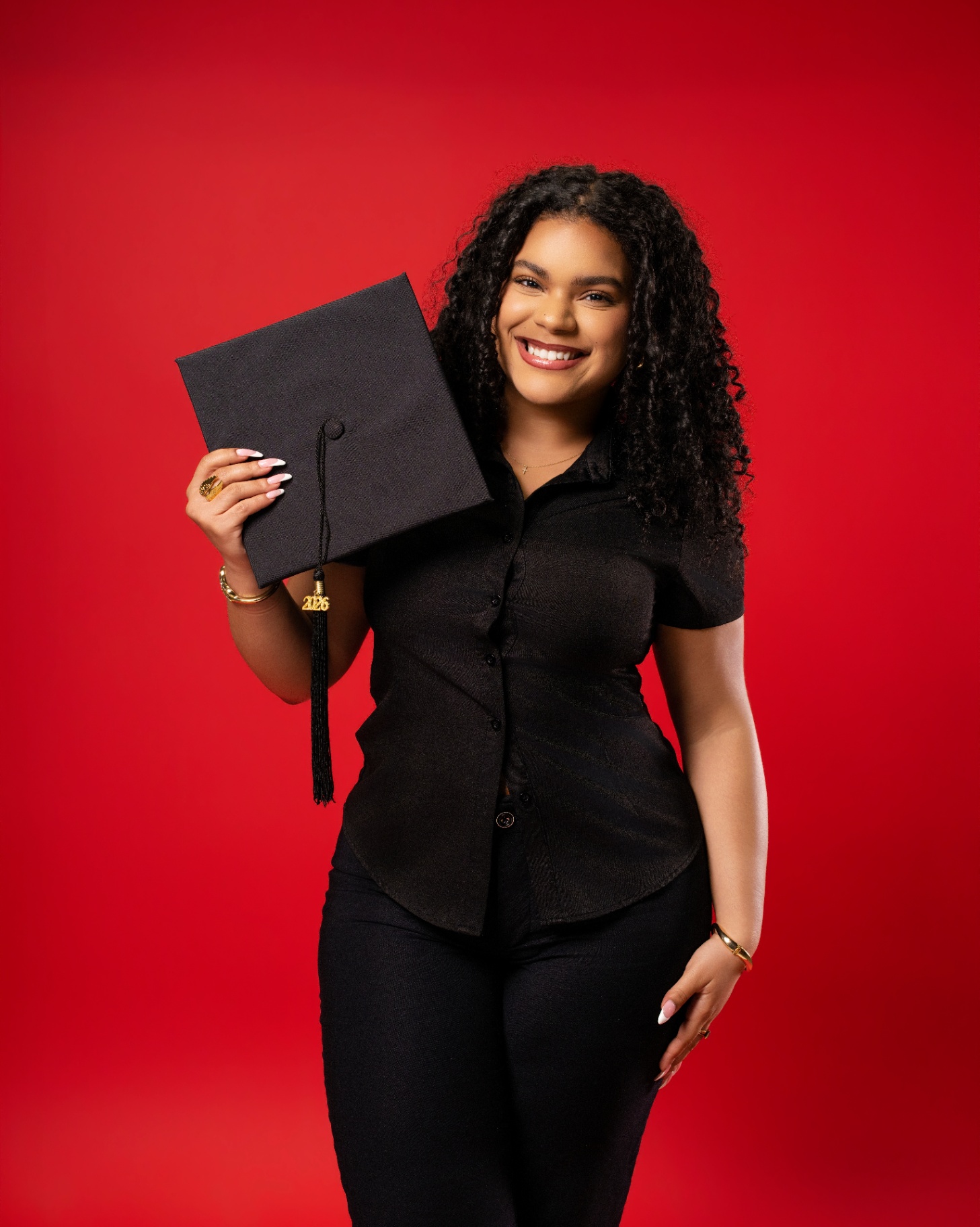 Graduate holding cap — red backdrop