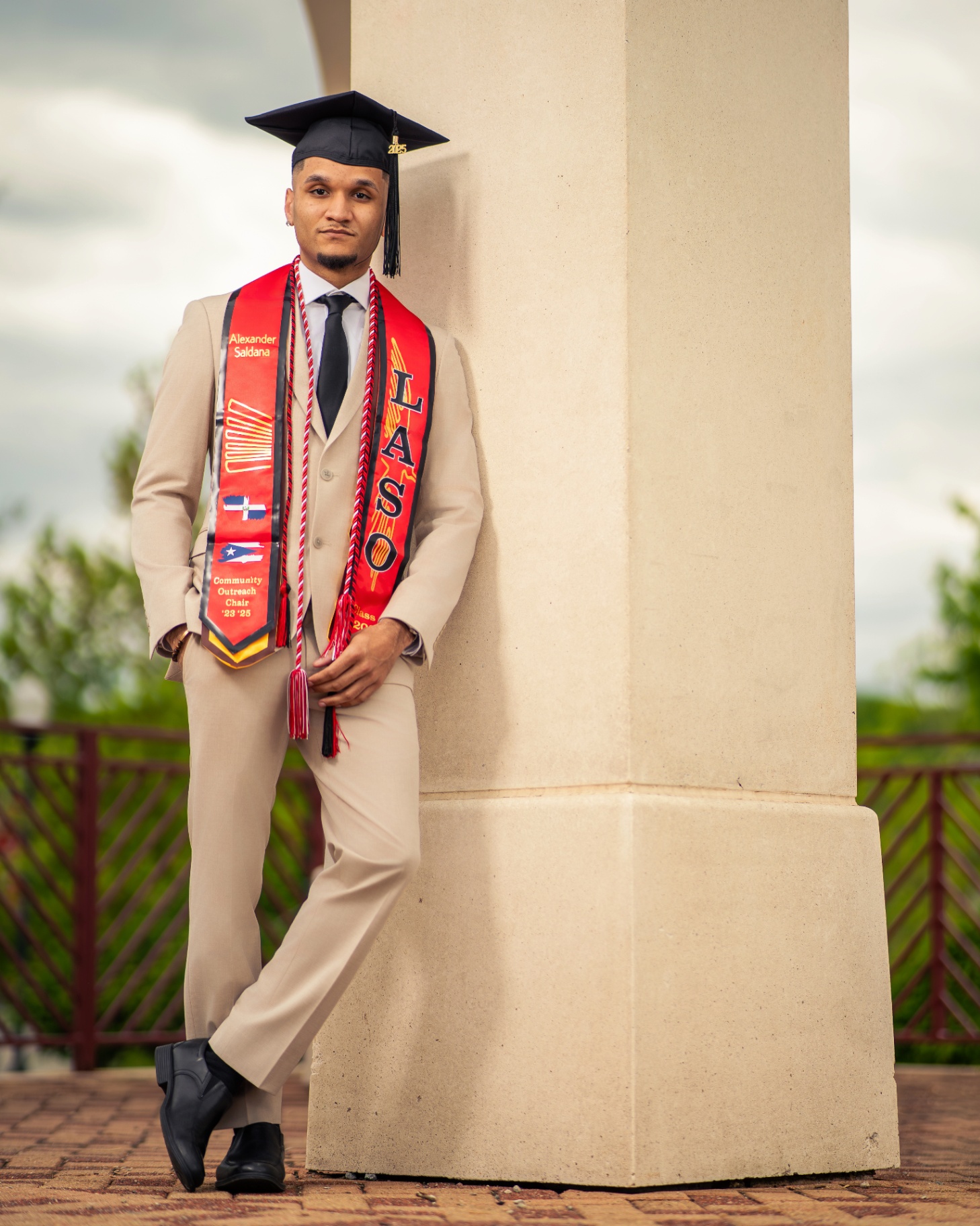 LASO grad in tan suit leaning against a column