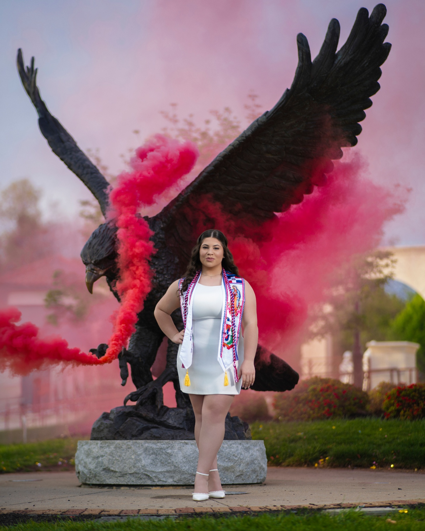 Grad in white dress with red smoke at eagle statue