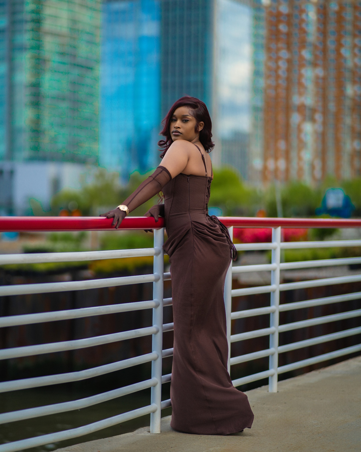Brown gown portrait on waterfront railing with skyline