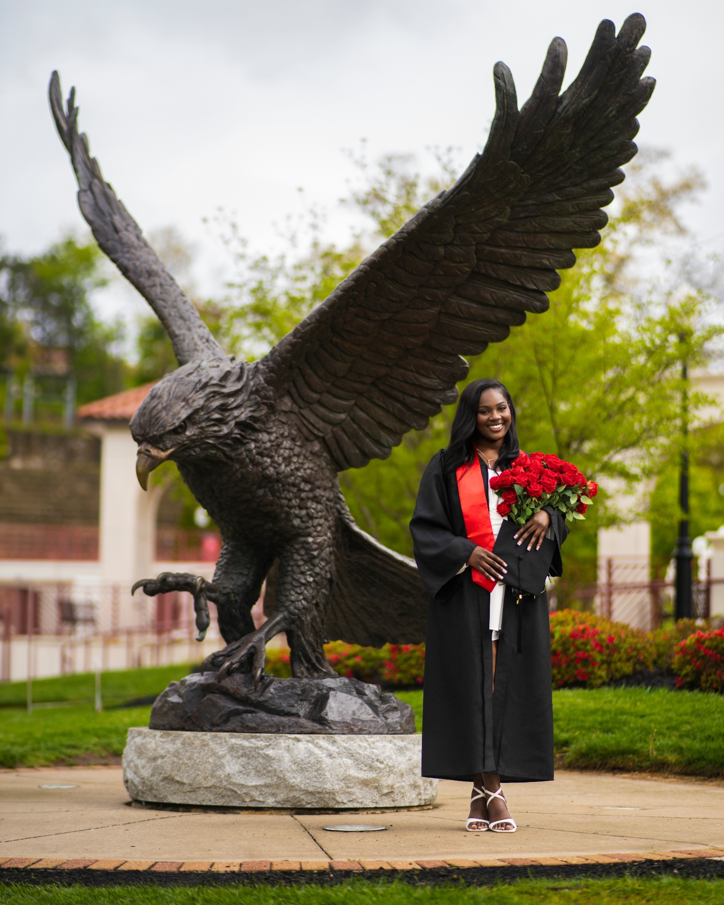 Graduate with red roses by Montclair eagle statue