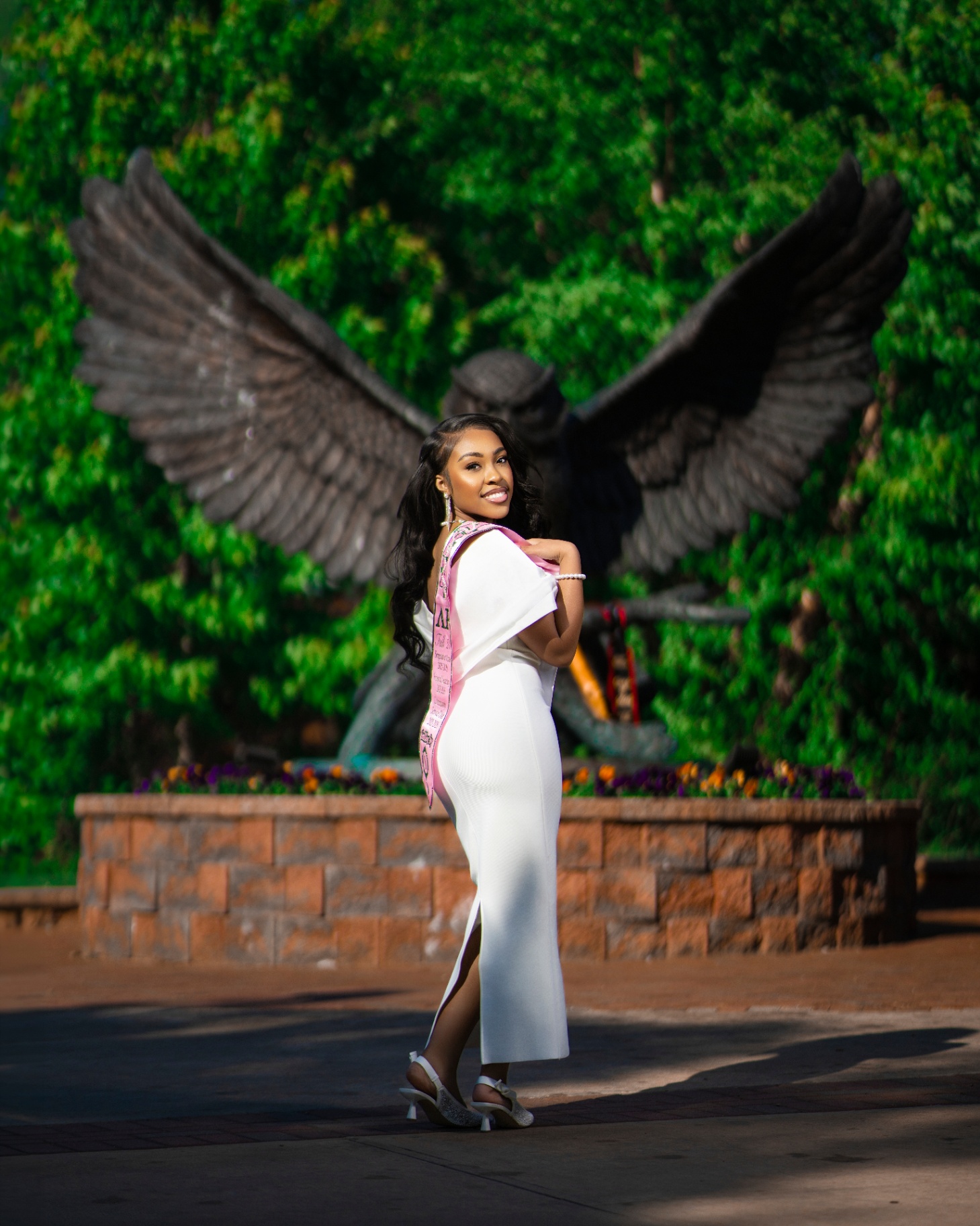 AKA grad in white dress by winged eagle statue