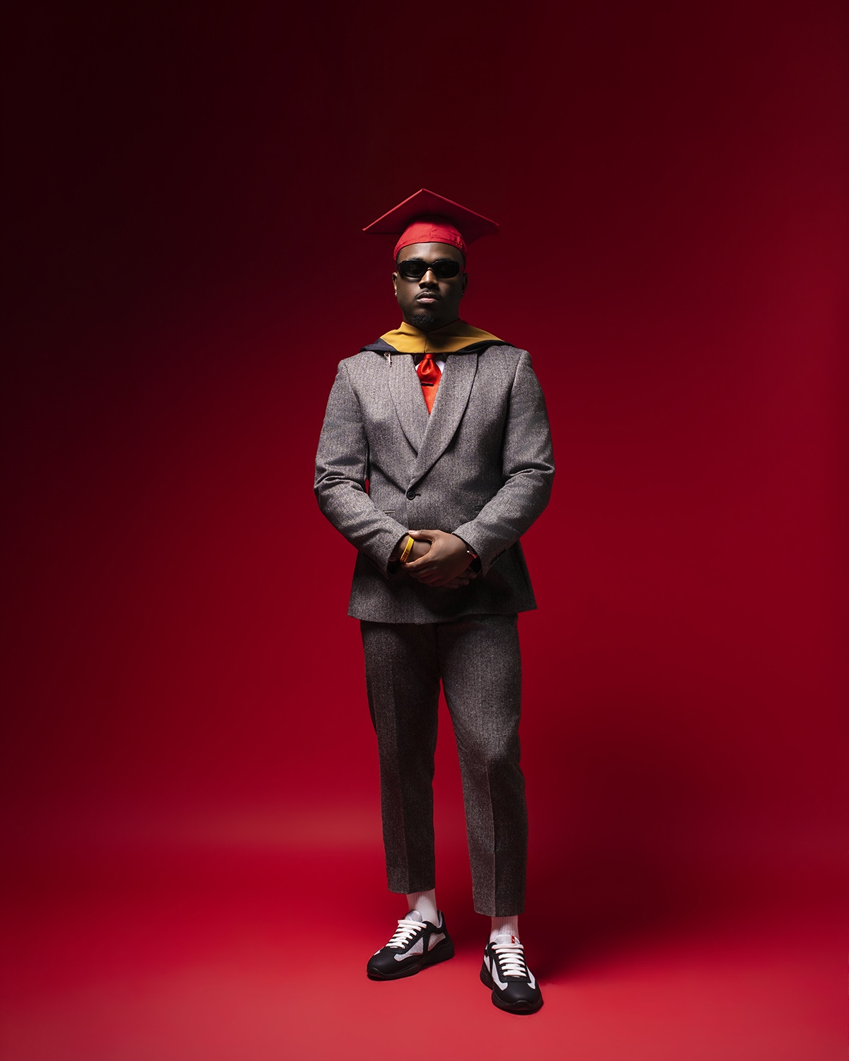Master's grad in gray suit on red backdrop
