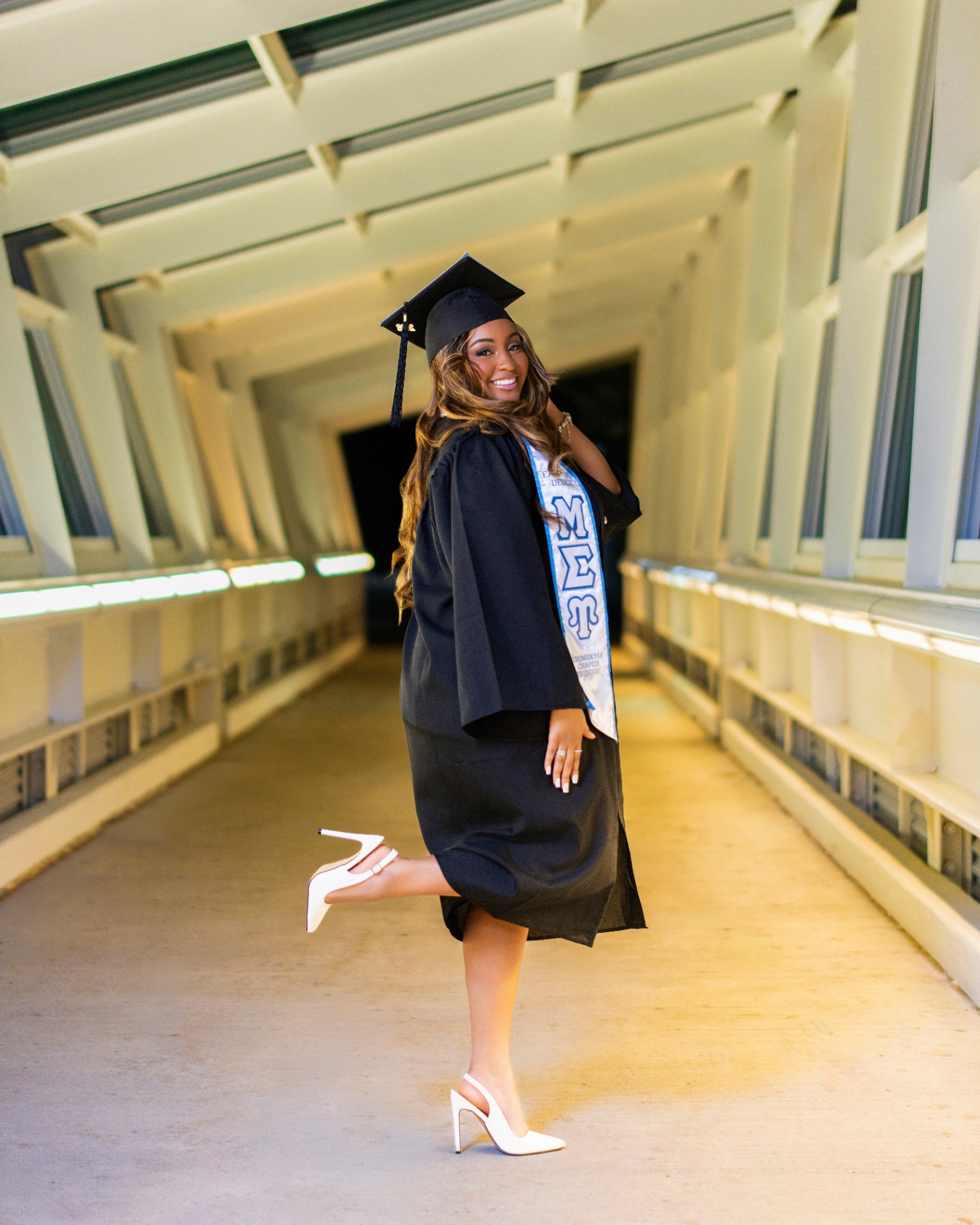 Sigma sorority grad in cap and gown on skywalk