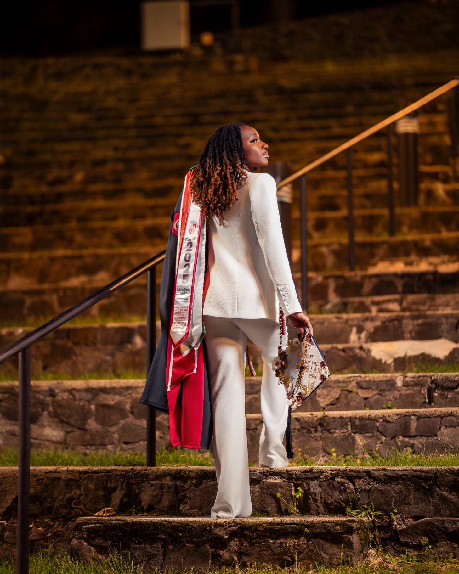 Public Health grad in white on stone steps
