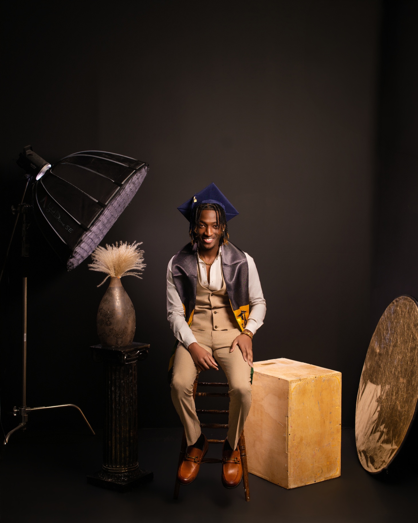 Graduate seated in studio with lighting and vase