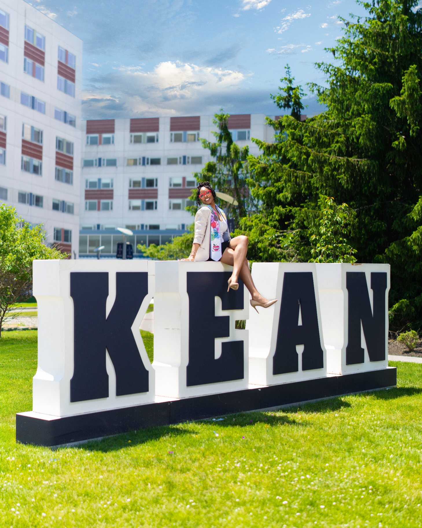 Kean grad sitting on giant KEAN letters sign