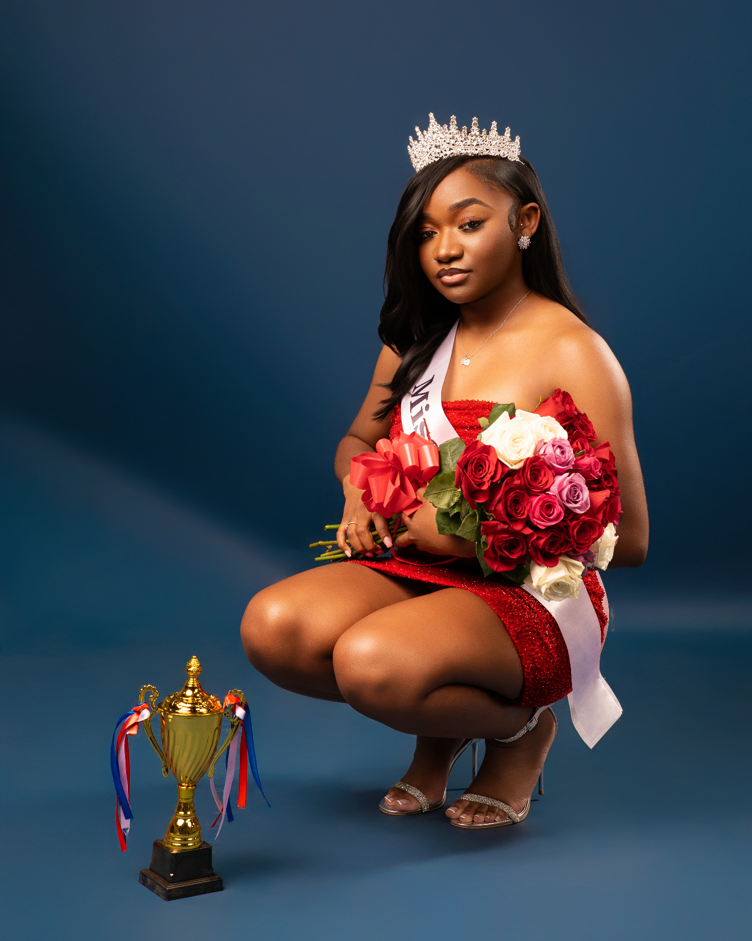 Pageant queen with crown, sash, roses and trophy