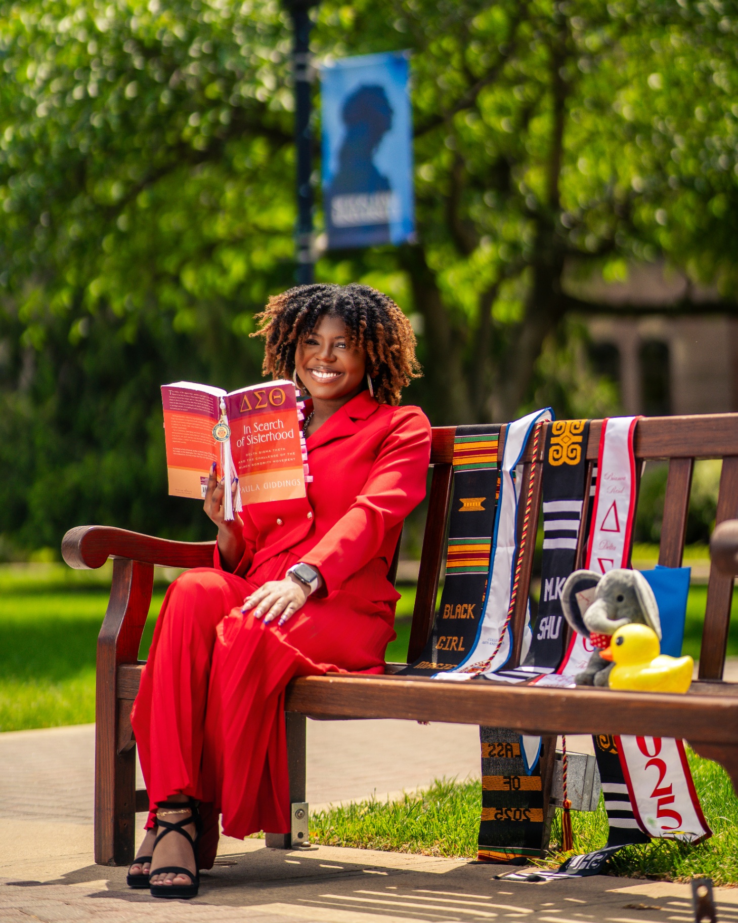 Delta Sigma Theta grad reading on bench with stoles