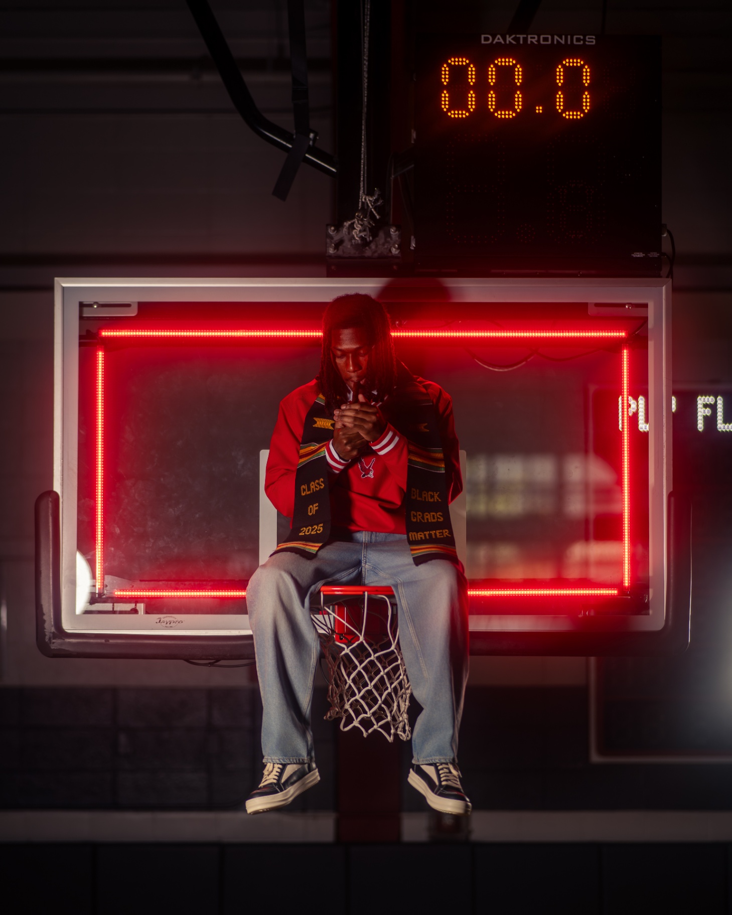 Athlete graduate seated on basketball rim with neon