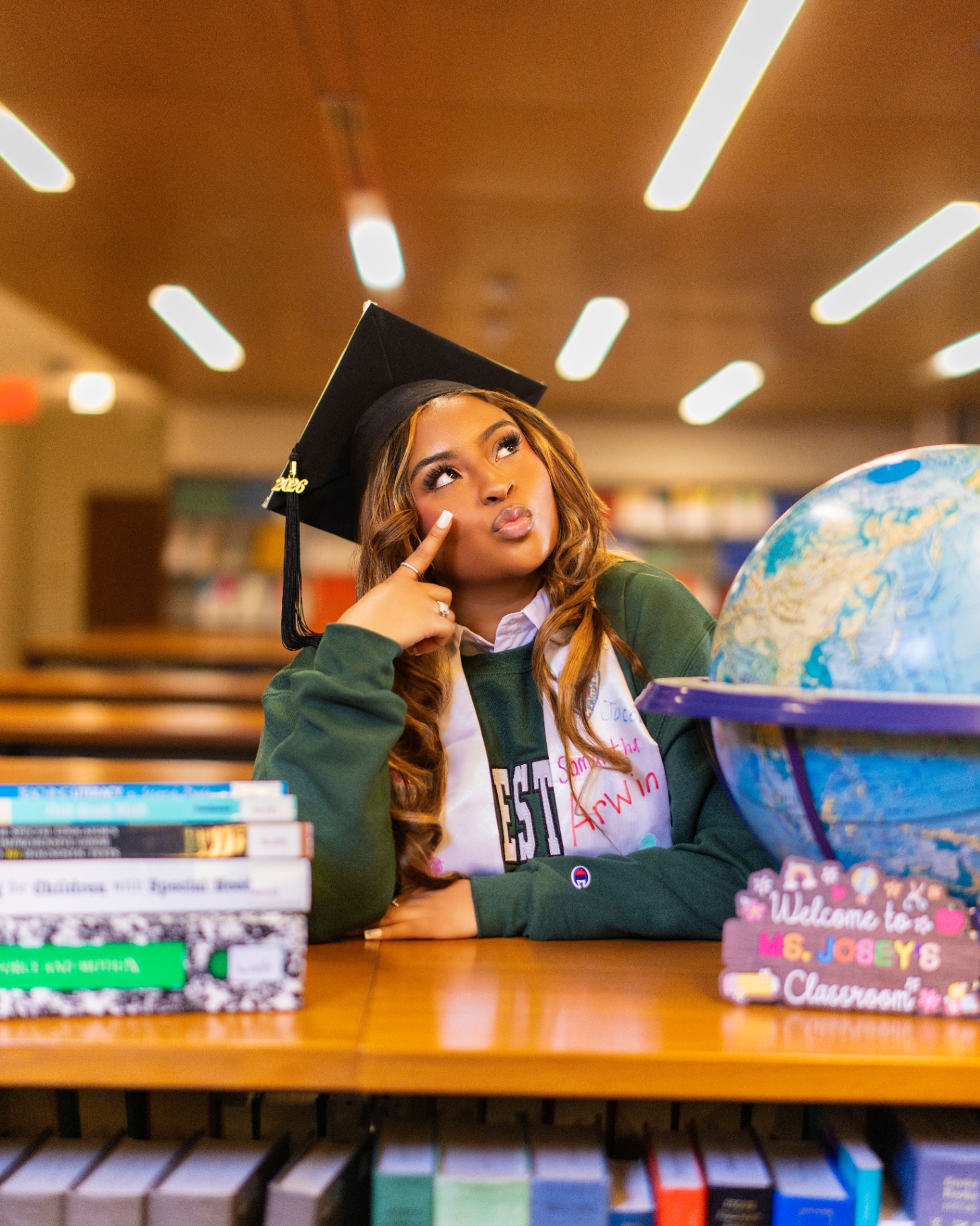 Future teacher grad in classroom with globe and books