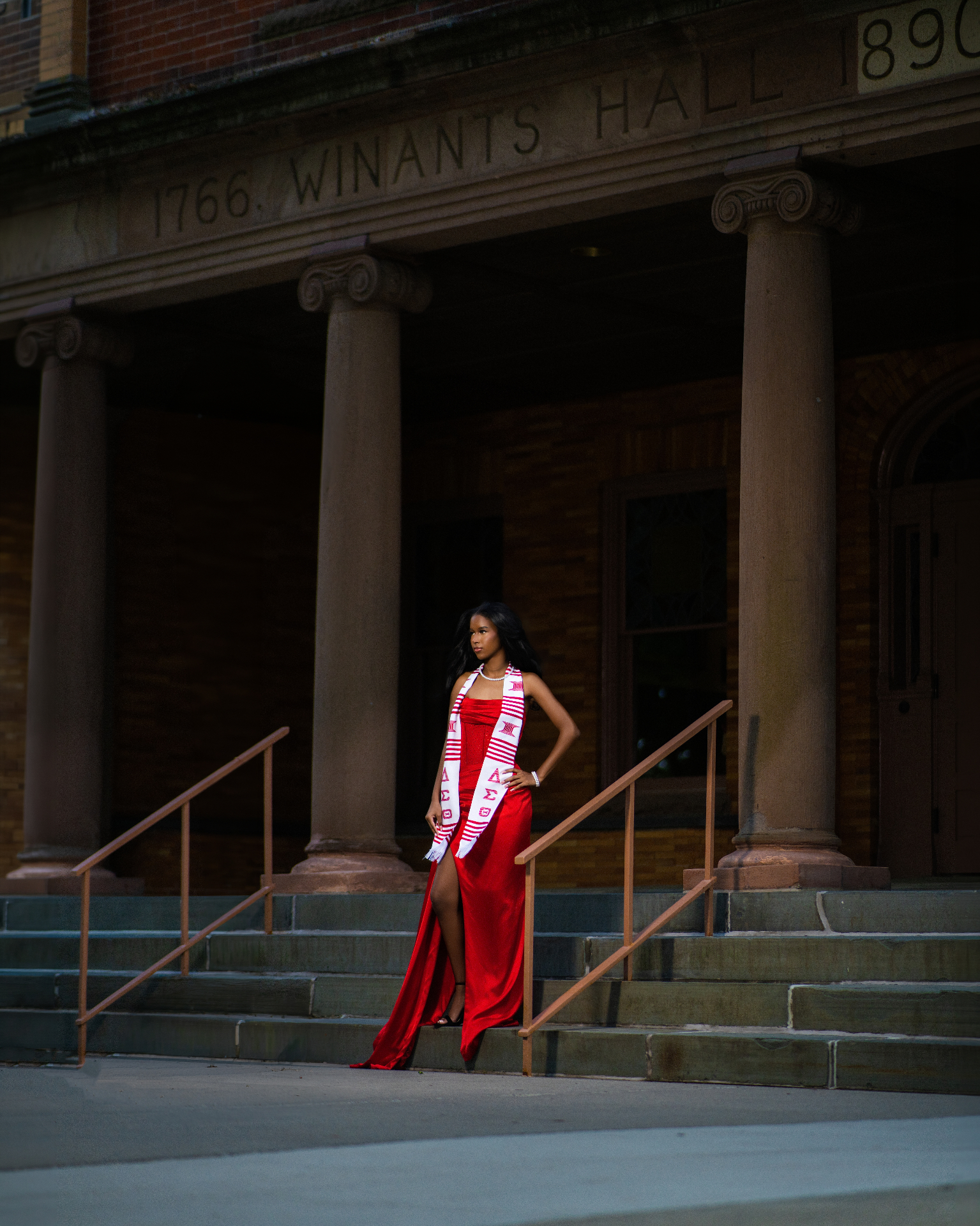 Delta grad in red gown on steps of Winants Hall
