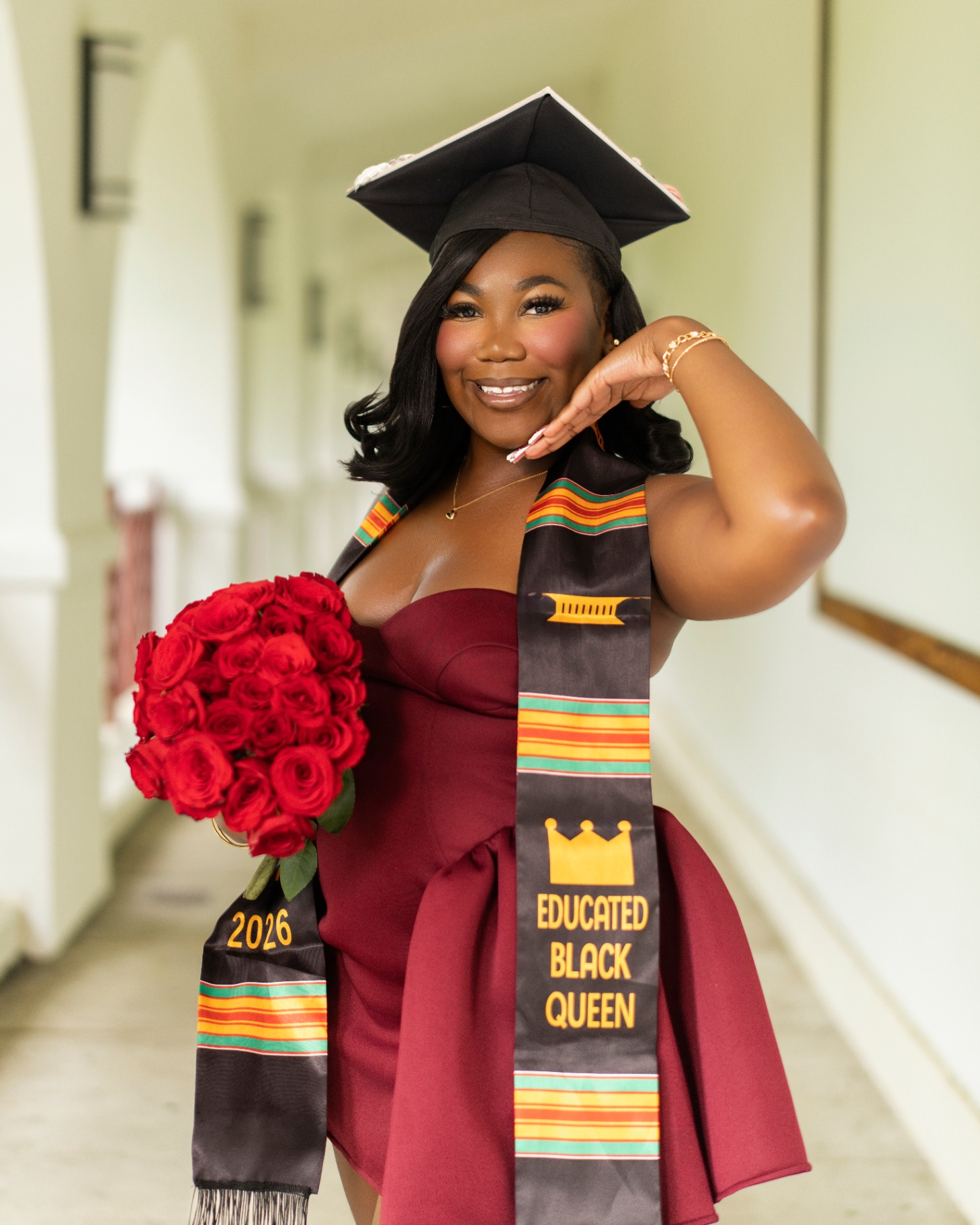 Educated Black Queen grad with red roses in corridor