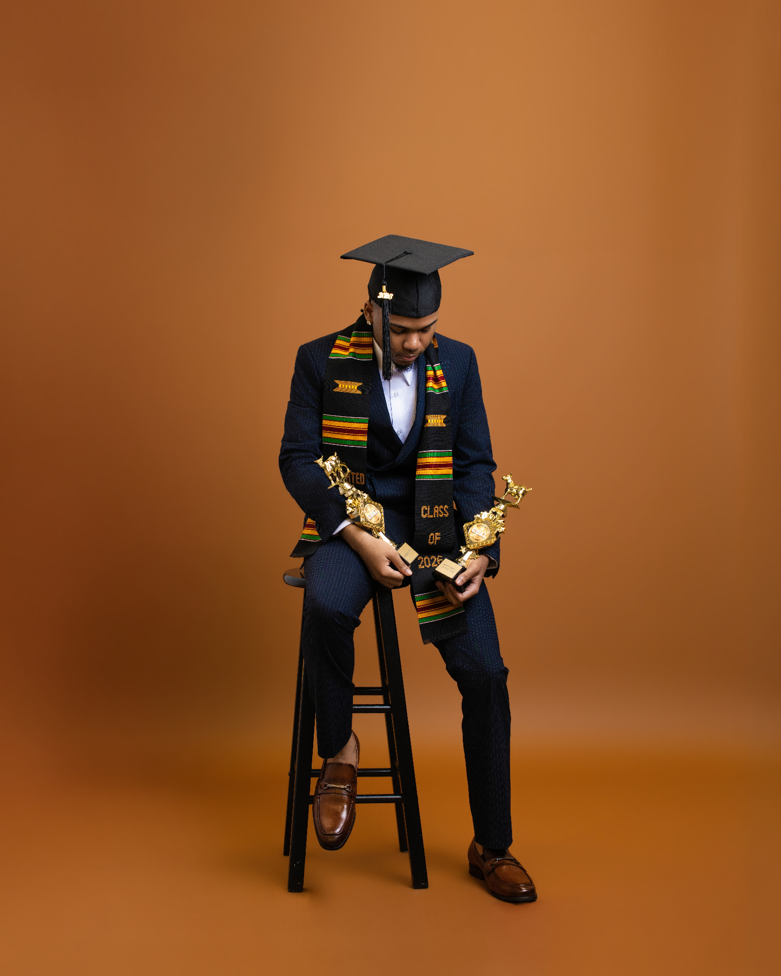 Graduate with trophies — orange backdrop