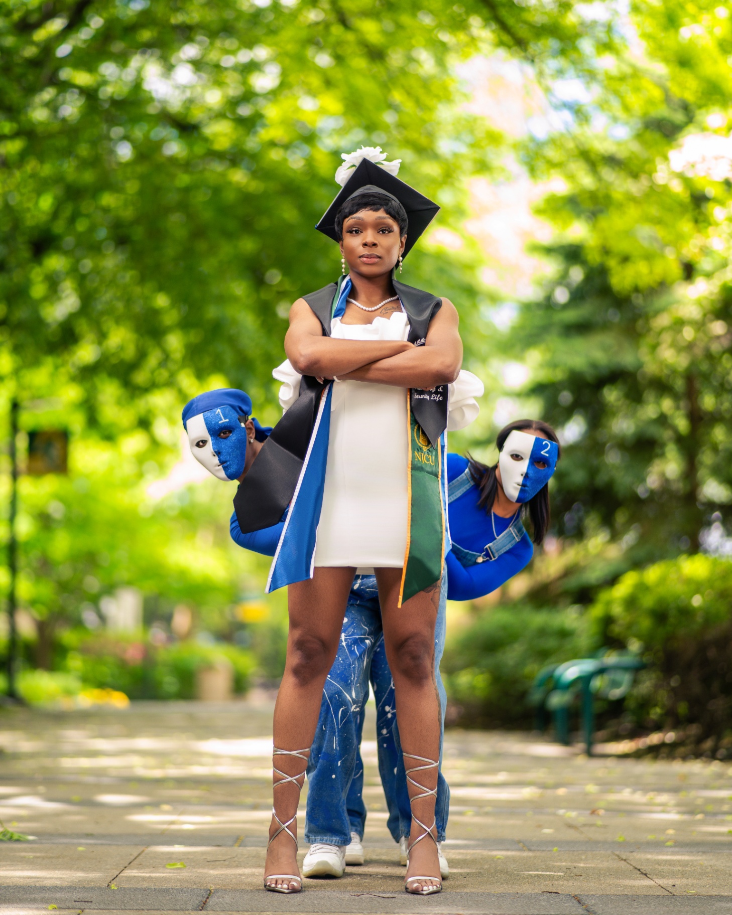 Graduate with masked figures on campus path
