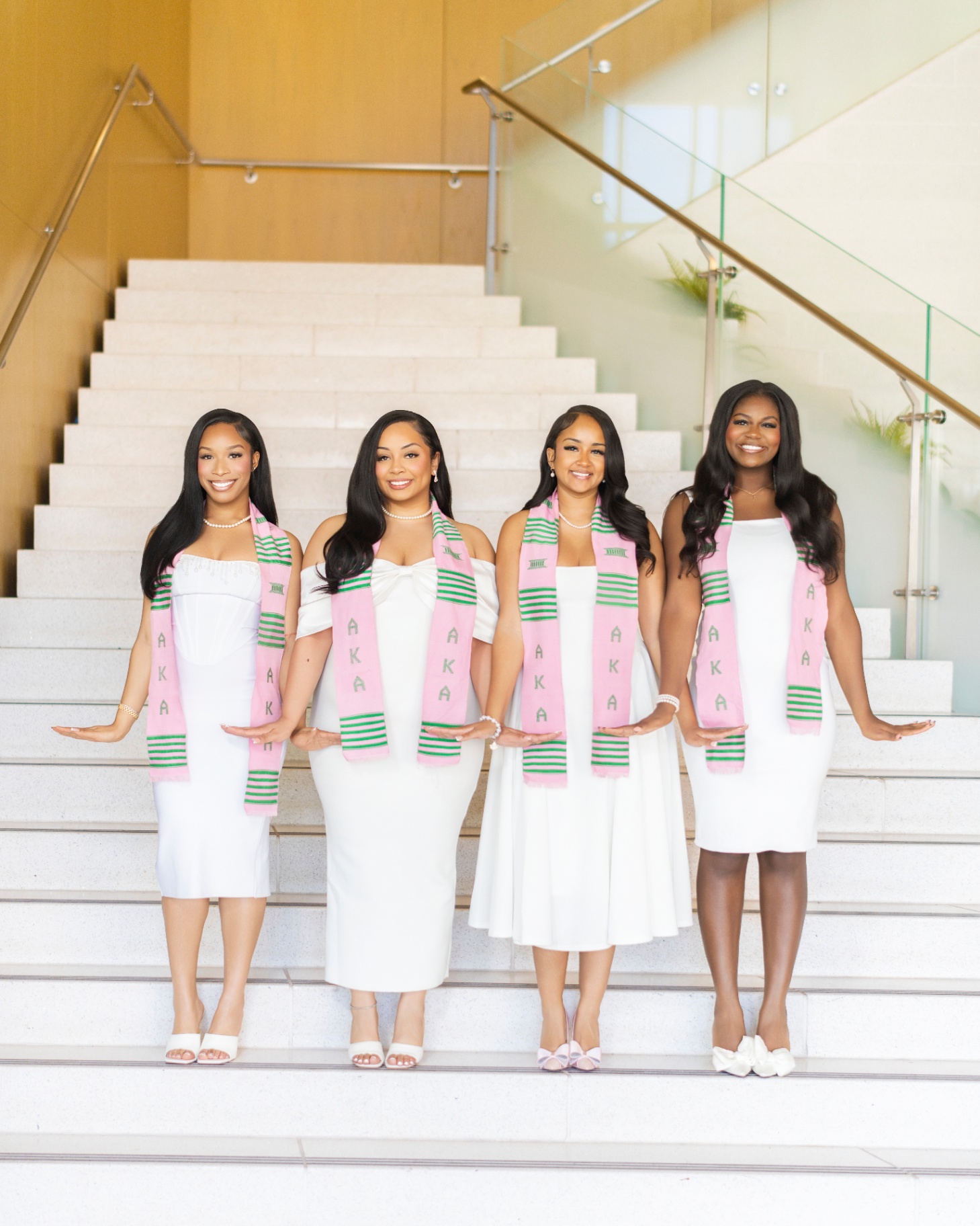 Four AKA sorority grads posing together on staircase