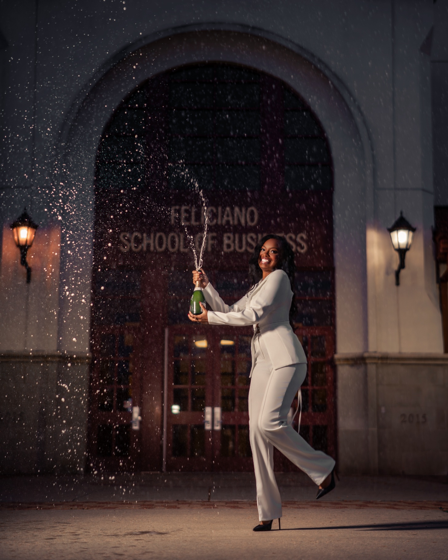 Feliciano grad popping champagne in white suit at night