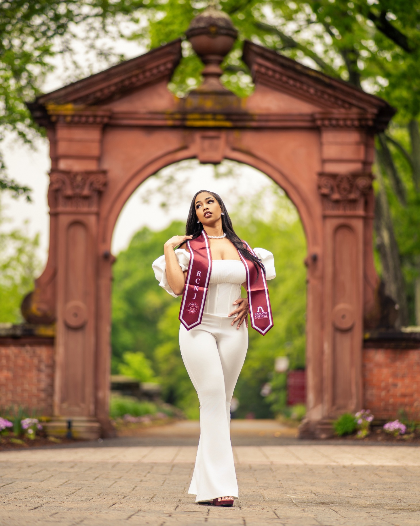Ramapo College grad in white under brownstone arch