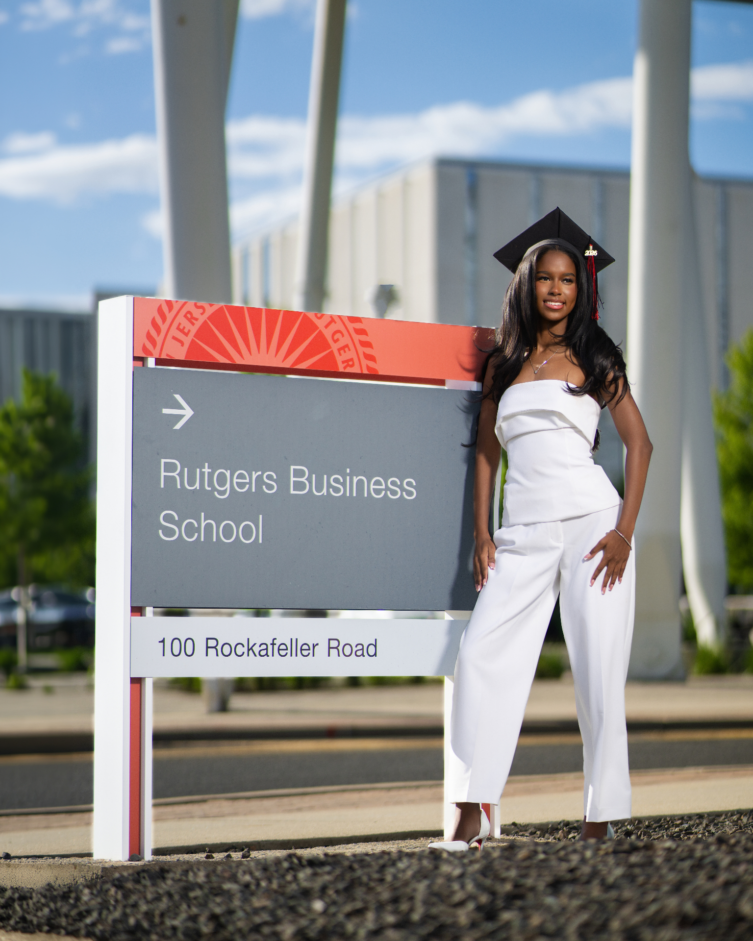 Rutgers Business School grad in white by campus sign