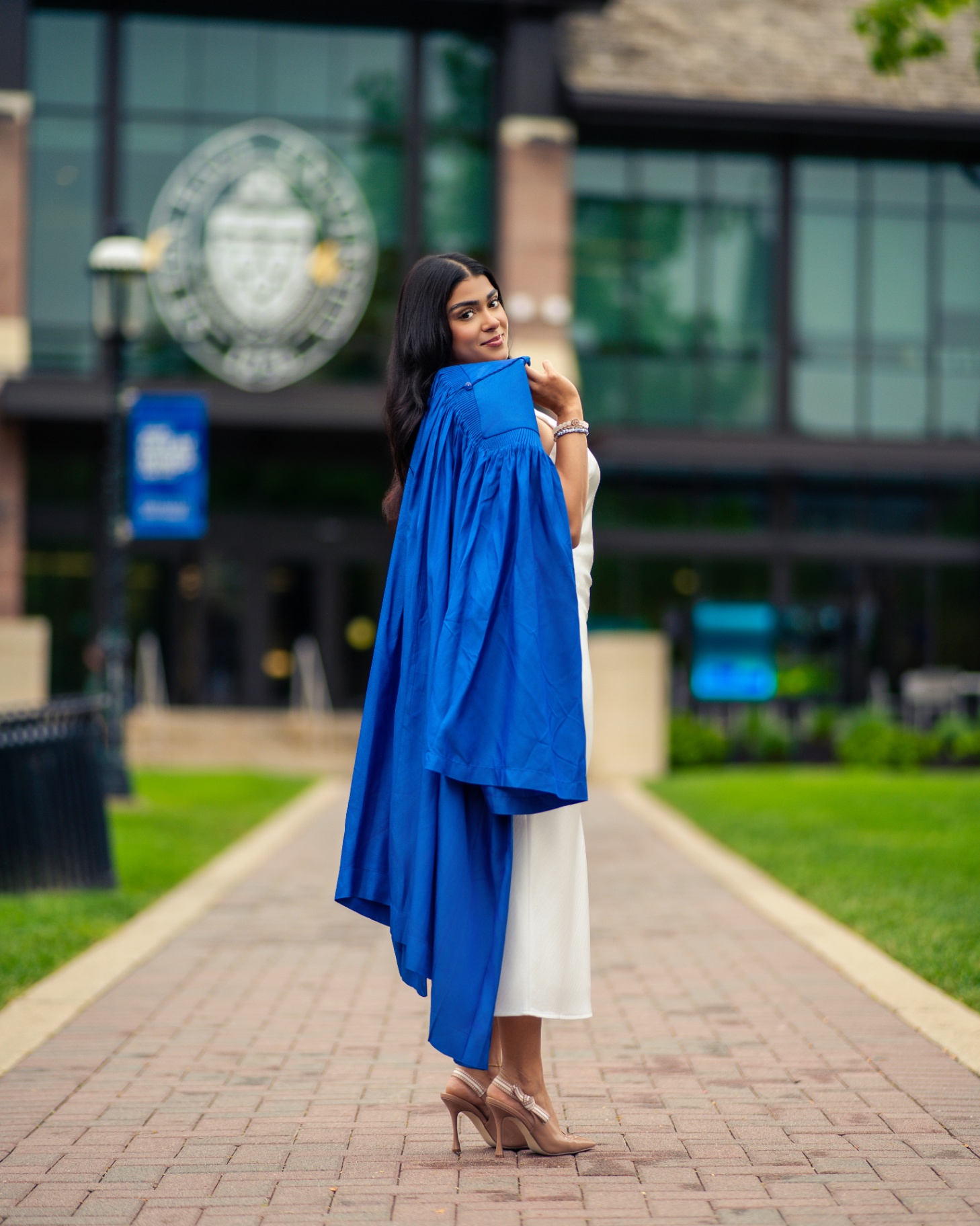 Seton Hall grad in white with blue gown on walkway
