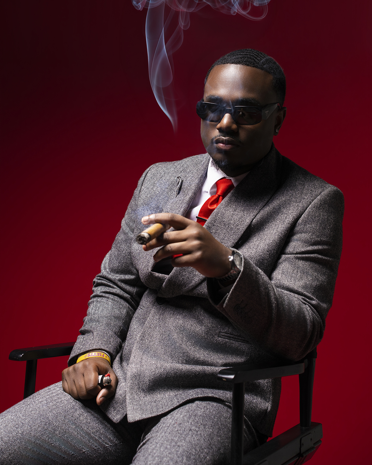 Herringbone suit portrait with cigar on red