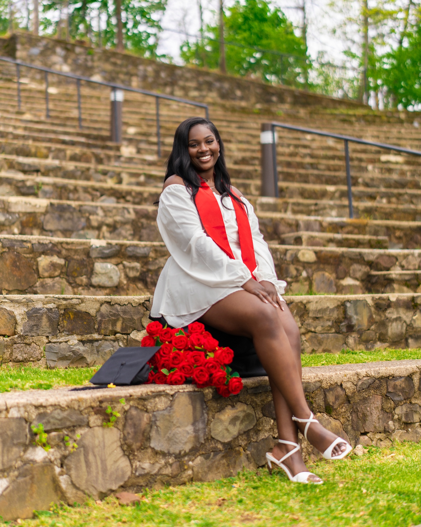 Graduate with red roses on stone amphitheater steps