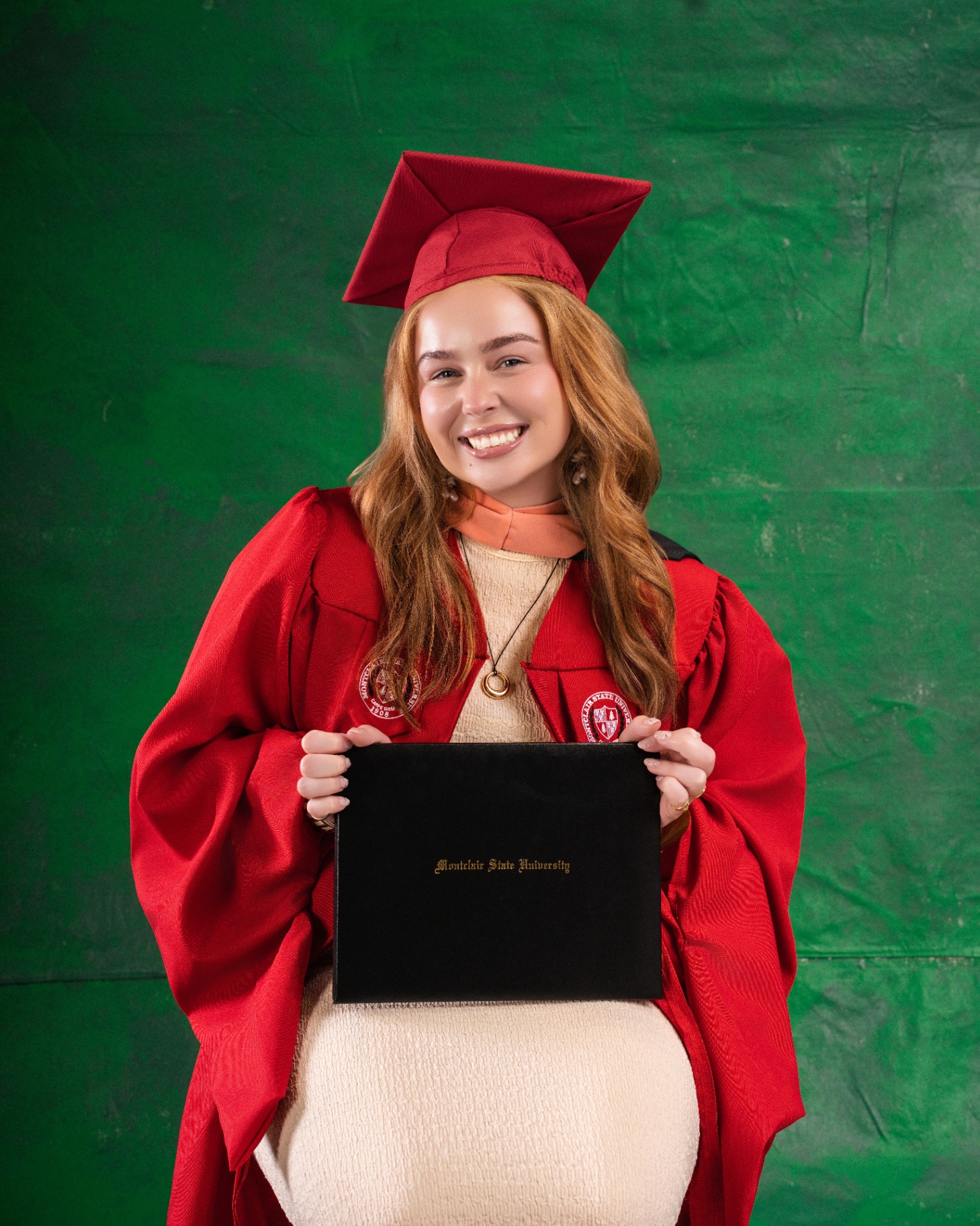 Montclair State graduate with diploma — green backdrop
