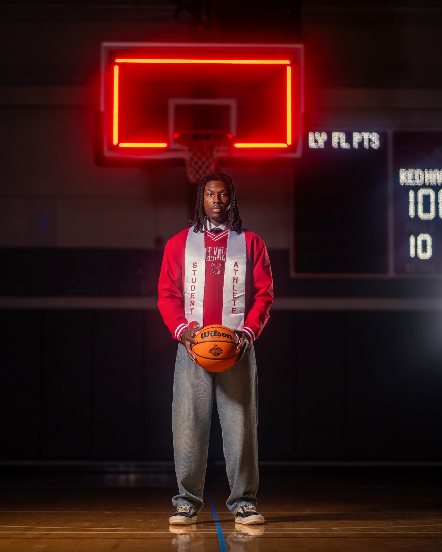 Student athlete with basketball under neon hoop