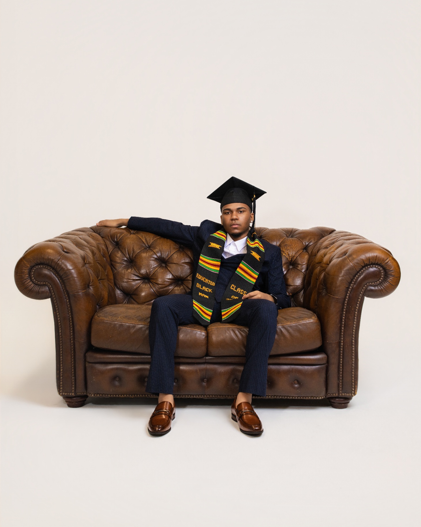 Educated Black Man graduate on Chesterfield sofa