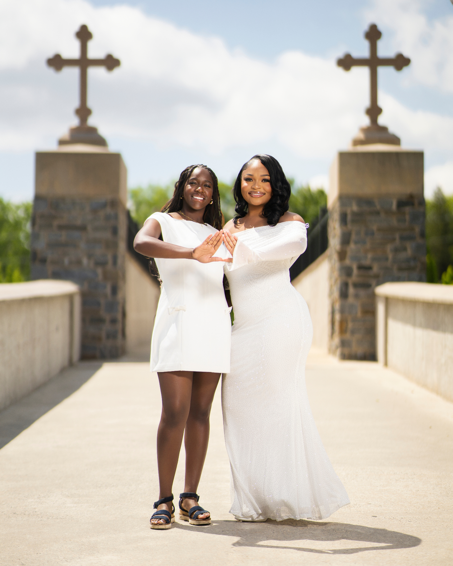 Two women in white dresses posing on stone bridge