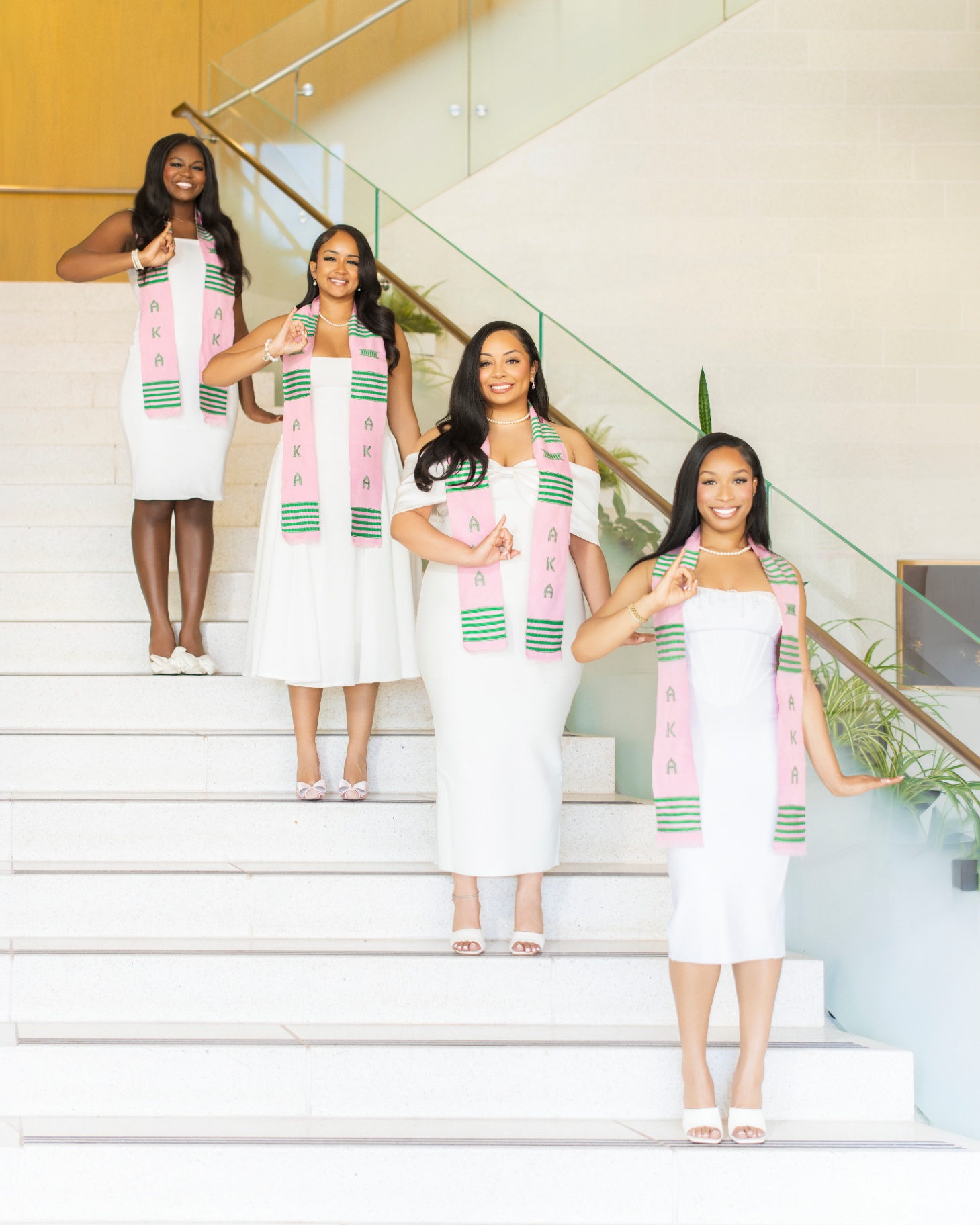 AKA line sisters on staircase throwing sorority sign